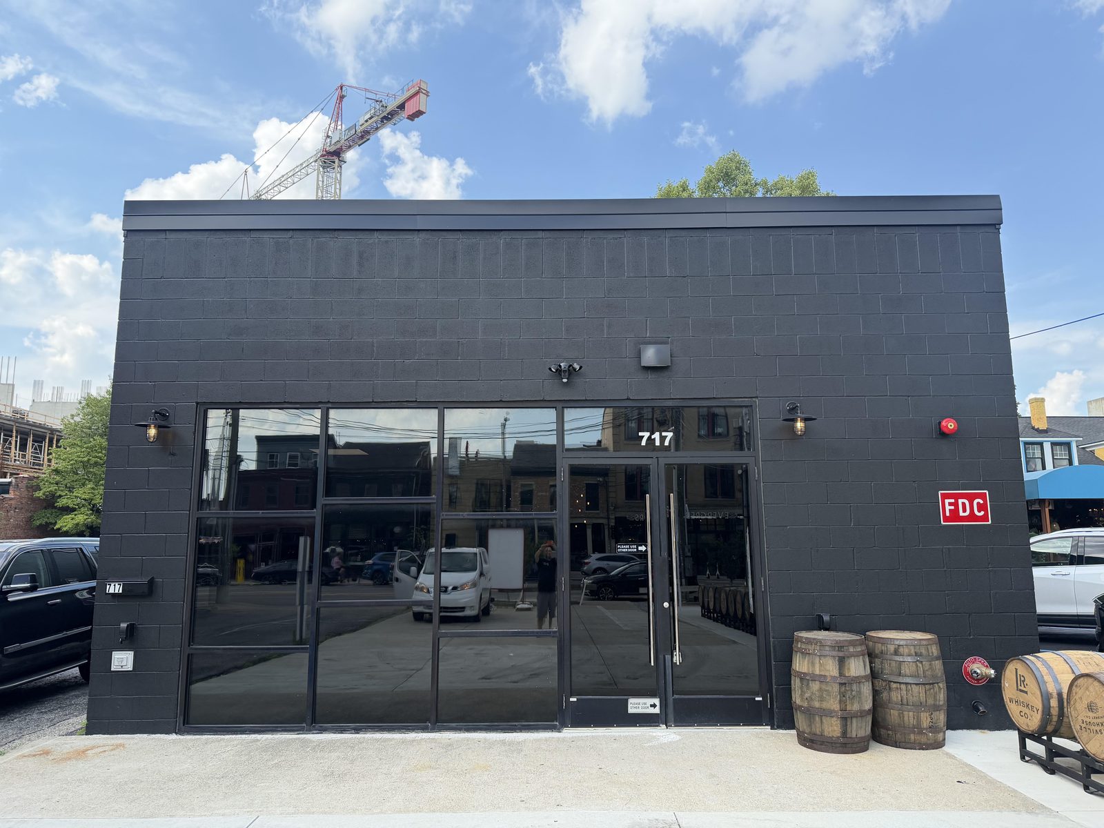 The front of 717 E Market Street in NuLu, Louisville — a renovated black building with whiskey barrels out front and no exterior sign installed.